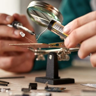 Techniker lötet Mikrochip auf Leiterplatte