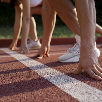 Zwei Läufer an der Startlinie, von denen nur die Beine und die Arme zu sehen sind