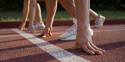 aufgestützte Hände von zwei Sportlern an der Startlinie