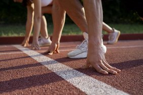 aufgestützte Hände von zwei Sportlern an der Startlinie