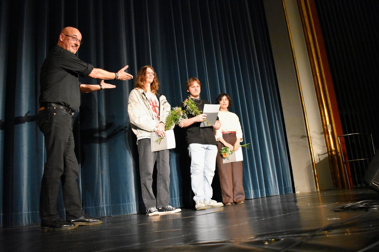Ein Lehrer zeigt auf seine Schüler auf der Bühne