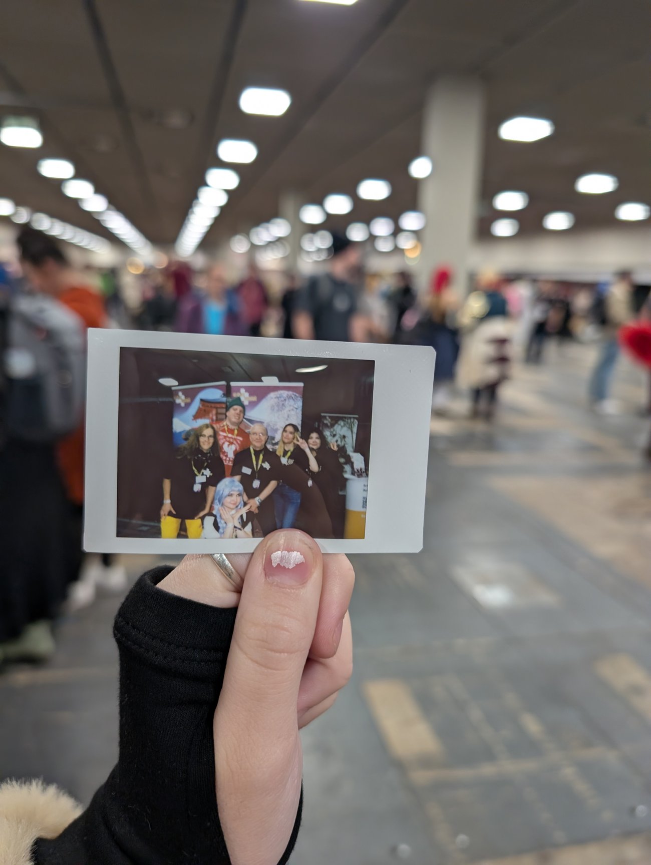 eine Hand hält ein Polaroid mit einer Gruppe von Menschen