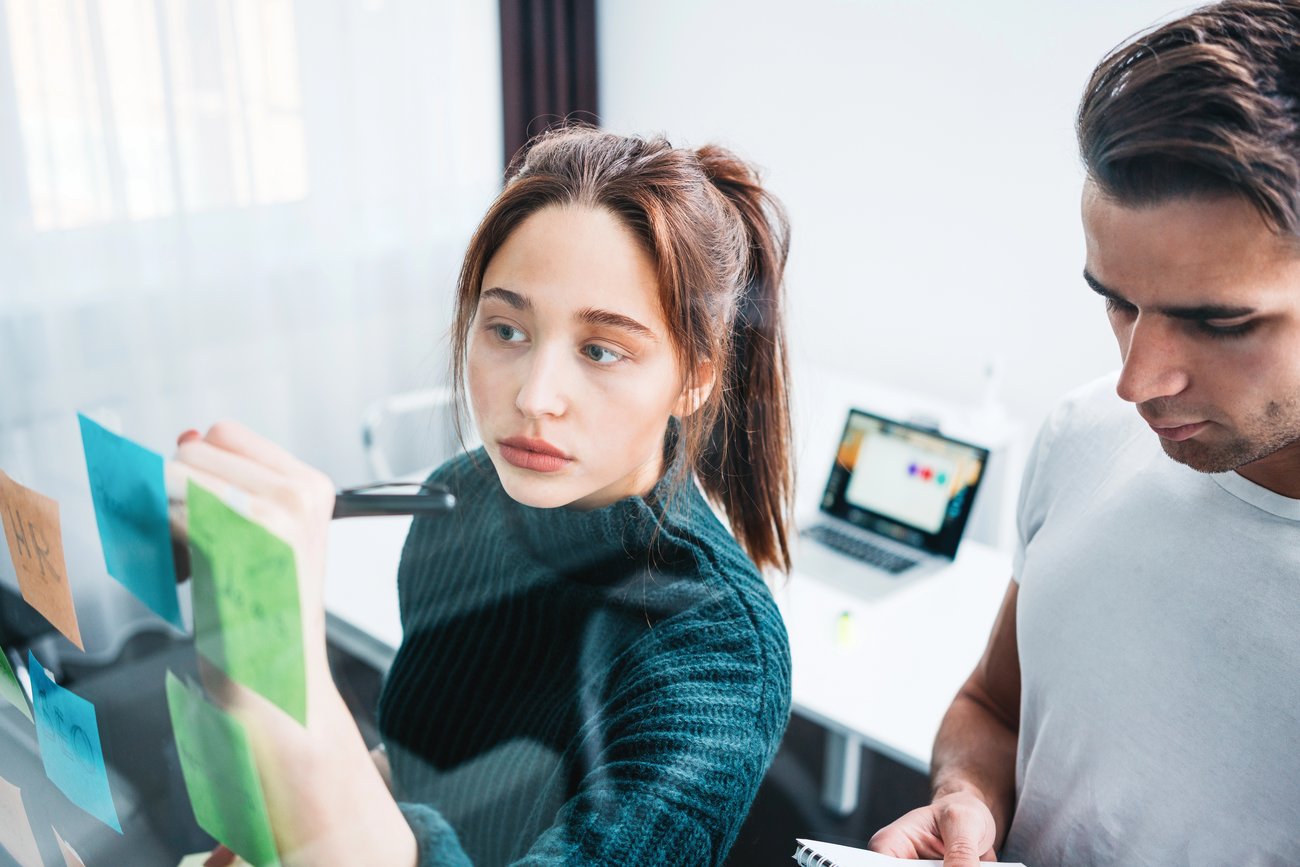 Kauffrau im Büro schreibt an Glaswand