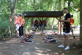 KLettergurte liegen auf dem Boden und einige Menschen schauen in den Wald