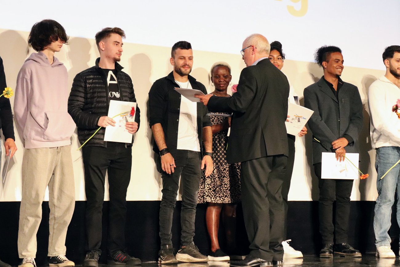 ein Lehrer überreicht auf der Bühne ein Zeugnis an einen Schüler