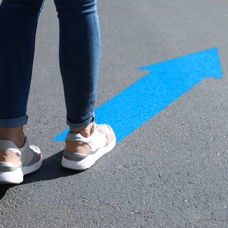 Beine auf Straßenpfeil