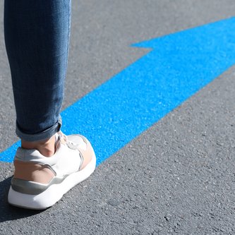 Beine auf Straßenpfeil