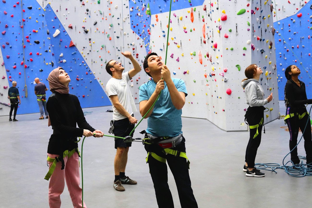 Schüler sichert Boulderin beim Klettern