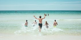 Menschen von hinten, die ins Meer rennen