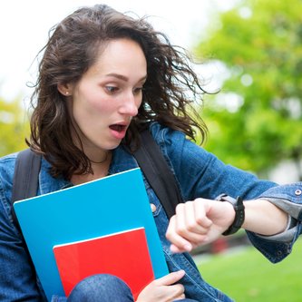 eine Frau guckt erschrocken auf ihre Armbanduhr
