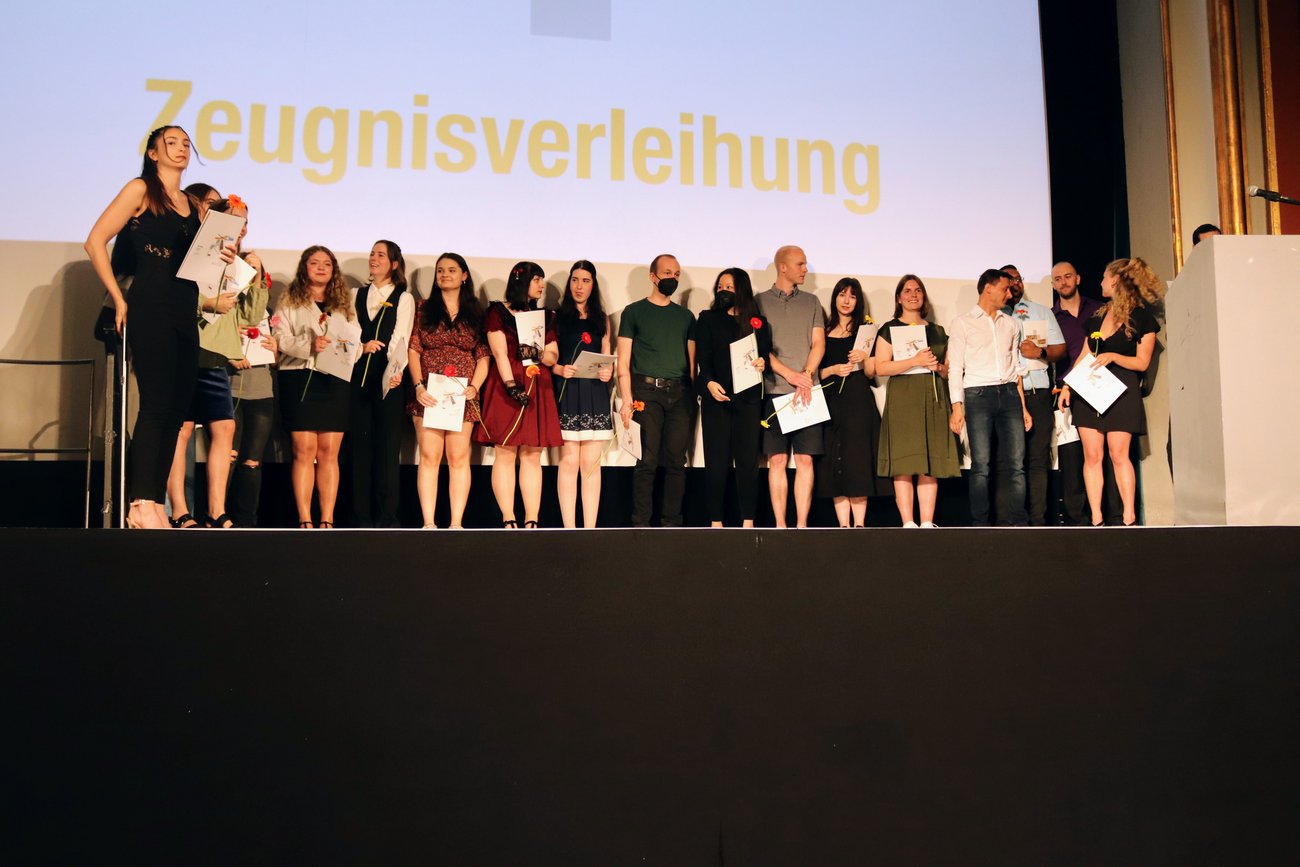 eine große Schülergruppe steht auf der Bühne mit Zeugnissen