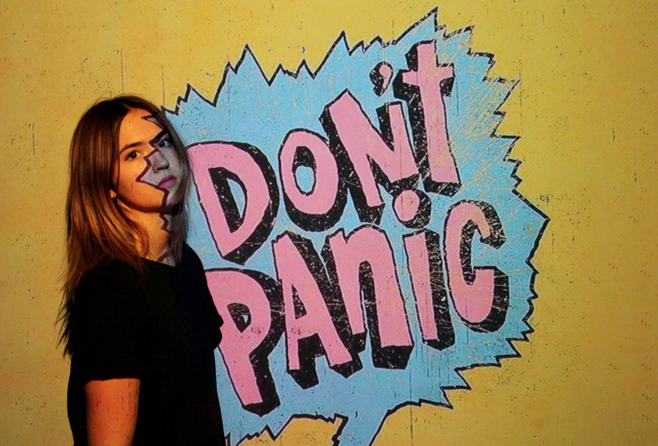 junge Frau vor Graffiti-Schriftzug "DON'T PANIC"