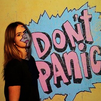 junge Frau steht neben Graffitischriftzug "Don't Panic"