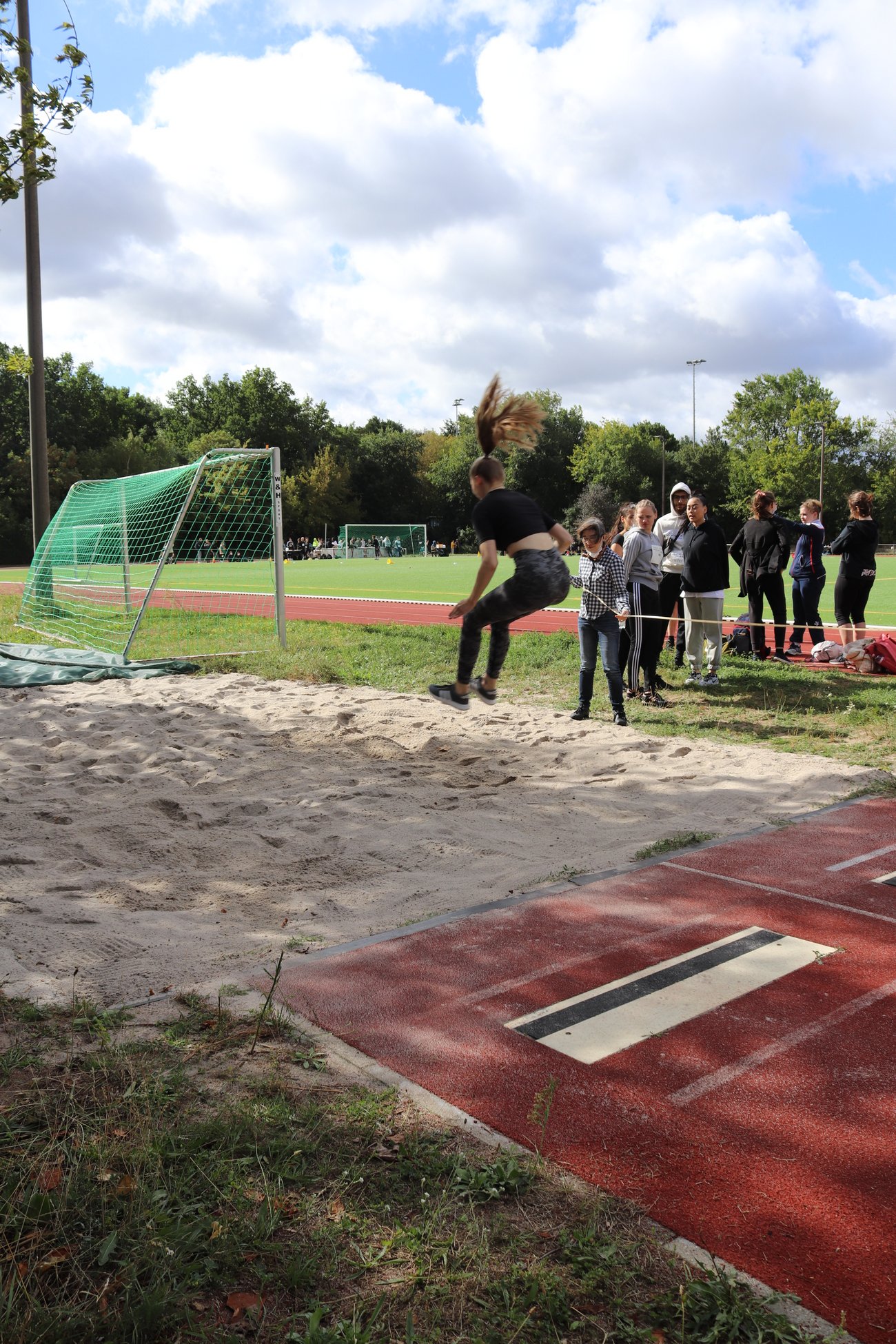 eine Schülerin von hinten, die in eine Weitsprunggrube springt