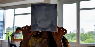 Gesicht von Schülerin hinter gemaltem Gesicht