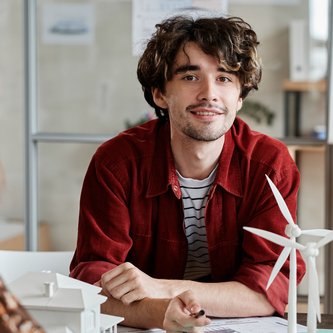 Energietechniker sitzt am Tisch mit Windradmodell
