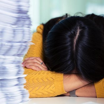 Überforderte Schülerin mit Kopf auf Schulbank