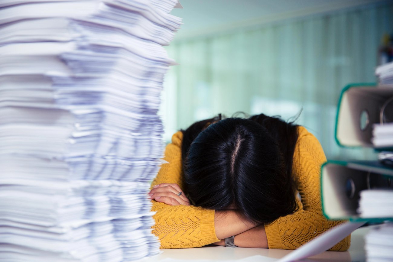Überforderte Schülerin mit Kopf auf Schulbank